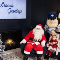 3 sisters sit on chair next to Santa smiling with Louie anchors up